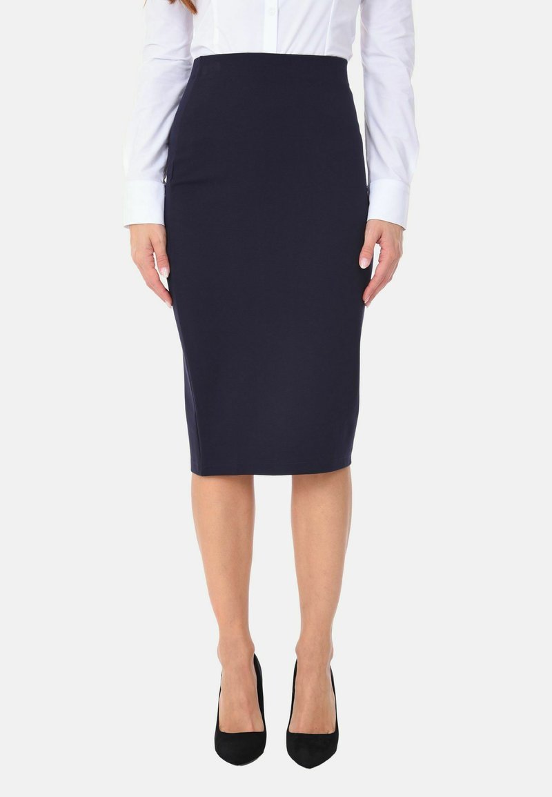 Gonna a matita blu navy, design aderente, lunghezza al ginocchio, realizzata in tessuto elasticizzato. Indossata con una camicia bianca con bottoni e scarpe con tacco alto nere.