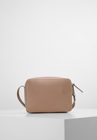 Borsa in pelle beige con forma rettangolare, manico a lato e chiusura con zip. Texture liscia con cuciture visibili.