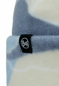 Gorra de forro polar con una textura suave, que presenta un patrón en azul y crema y una etiqueta negra del logo de Buff en el lateral.