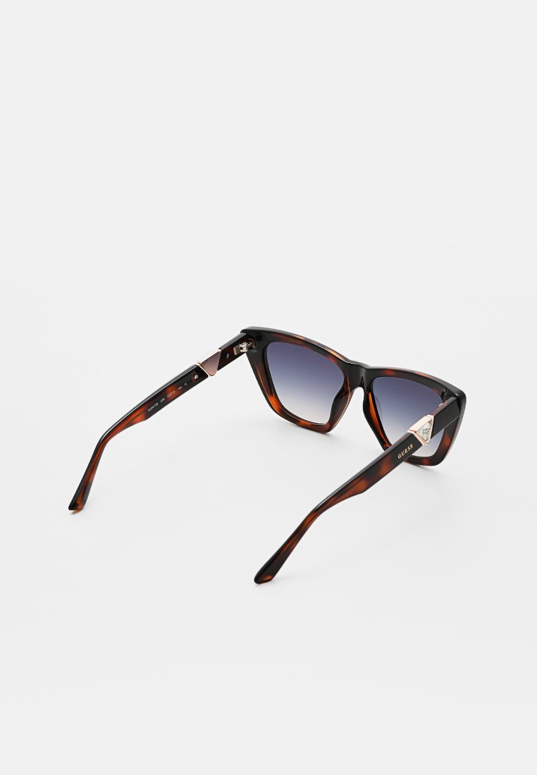 Lunettes de soleil en écaille de tortue avec des montures angulaires, des verres dégradés foncés, des accents en métal et un détail de logo sur les branches.