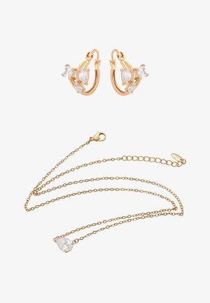 Boucles d'oreilles créoles en or avec pierres précieuses transparentes et collier chaîne assorti en or avec un pendentif unique en forme de poire en pierre précieuse transparente.