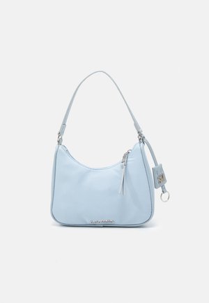 Sac à bandoulière bleu clair en matériau lisse, présentant une forme incurvée, une fermeture éclair supérieure et des accents métalliques. Logo de la marque affiché à l'avant.