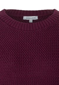 Pull en tricot bordeaux avec un motif texturé, un col rond côtelé et une étiquette indiquant la marque et la taille.