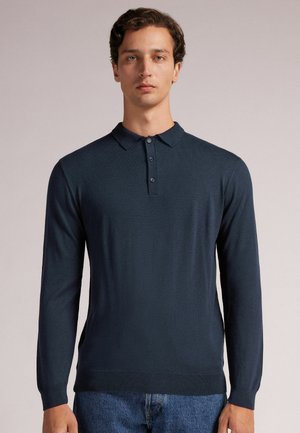 Strikket langærmet polo shirt i mørkeblå, med klassisk krave, tre-knaps lukning og ribbede manchetter. Blød tekstur og tætsiddende design.