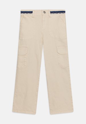 Beige bukser med vide ben med forlommer med klap på benene og blå mønstret indvendigt linning, der lukkes med knap og lynlås.