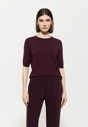 Burgundy short-sleeve sweater in a smooth knit fabric, paired with matching corduroy trousers featuring vertical stripes and a relaxed fit.