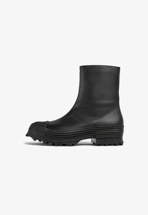 Black ankle boot made of smooth leather with a structured, ribbed sole and rounded toe, featuring a textured finish and durable tread.