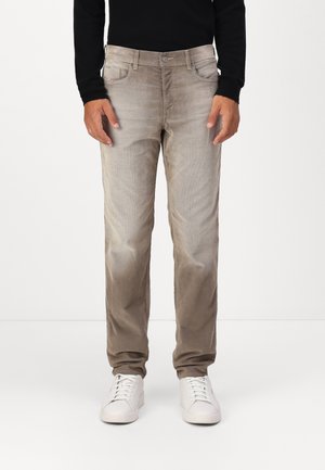 Pantalons en denim beige clair avec une coupe droite, dotés de poches avant, d'une fermeture à bouton et d'une fermeture éclair, et de baskets blanches. Texture lisse.