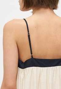 Roșie și bej, rochie cu bretele ajustabile, un corset ajustat și un material plisat curgător în partea de jos.