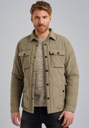 Chaqueta acolchada verde oliva con botones a presión negros, dos bolsillos en el pecho y un suéter de punto texturizado debajo.