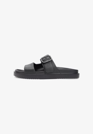 Sort sandal med bred rem og justerbar spænde, med en tekstureret fodseng og en tyk, rillede sål for forbedret greb.