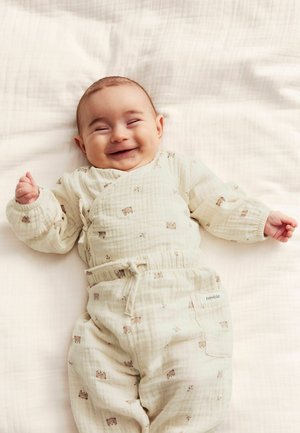 Ensemble pour bébé de couleur beige clair avec un design enroulé, des manches longues et une taille élastique, orné de petits motifs d'ours et d'un tissu texturé.