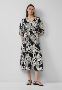Zwart-wit bloemenjurk met V-hals, puffmouwen en een getailleerde taille. Beschikt over een gelaagde rok met een ontspannen silhouet.