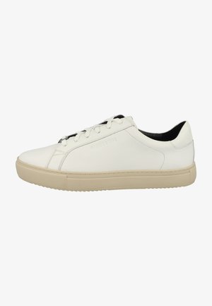Zapatilla de cuero blanca con punta redondeada, suela de goma beige plana y diseño minimalista, que presenta un interior negro y cierre con cordones.