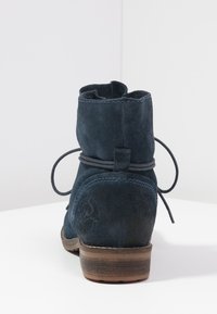 Granatowe zamszowe botki za kostkę z okrągłym noskiem, ozdobnym przeszyciem i małym obcasem, z wiązaniem z tyłu.