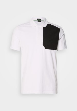 Weißes Poloshirt mit einem schwarzen strukturierten Patch auf der linken Brust, klassischem Kragen und einer Knopfleiste mit drei Knöpfen.