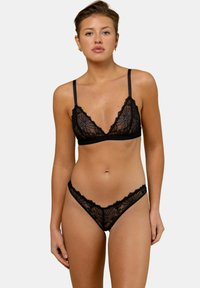 Ensemble bralette et string en dentelle noire avec des motifs floraux délicats, des bonnets triangulaires, des bretelles réglables et des bords festonnés.