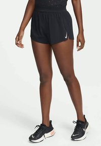 Černé sportovní šortky vyrobené z lehkého materiálu, se širokým pasem, bočními rozparky a malým bílým logem Nike na lemu.