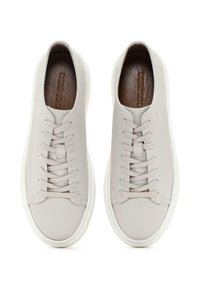Baskets en cuir gris clair avec semelles en caoutchouc blanches, bout rond et lacets plats. Tige texturée avec de subtils détails de couture.