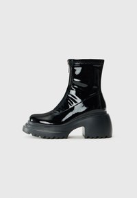 Glossy black platform ankle boot with rounded toe, chunky heel, zipper closure, and thick ridged sole against a white background.