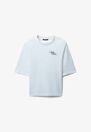 T-shirt blanc à manches courtes en coton avec une coupe décontractée. Il présente un petit design de texte scripté noir sur la zone gauche de la poitrine.