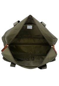 Borsa di stoffa verde oliva con un ampio interno aperto, caratterizzata da una superficie liscia, tasche interne e dettagli in pelle marrone.