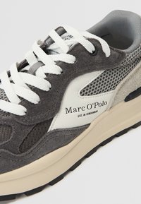 Sneaker grigio realizzato in materiali scamosciati e in rete, con accenti bianchi, lacci spessi e suola in gomma nera; presenta il logo del marchio di lato.