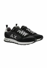 Schwarze und graue Sportschuhe mit einem Obermaterial aus Wildleder und Mesh, verstärkter Zehenkappe und einer strukturierten weißen Sohle mit einem dreieckigen Muster.