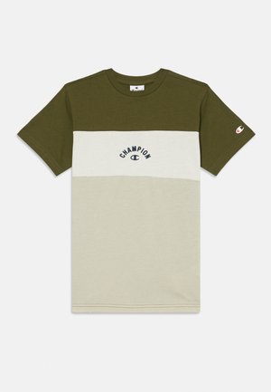 Olīvu zaļš un krēmkrāsas krāsu bloku kokvilnas T-krekls ar "Champion" logo tumši zilā krāsā. Īsas piedurknes un klasiskas apaļas kakla dizains.