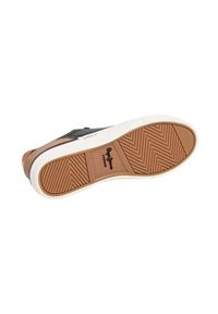 Zapatilla con suela de goma y suela exterior marrón texturizada. Parte superior negra con detalles en marrón y blanco. Presenta un diseño clásico con cordones.