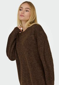 Brun strikket sweater med en løs pasform, brede ærmer og en rund halsudskæring. Blød tekstur og subtil farvevariation gennem hele stoffet.