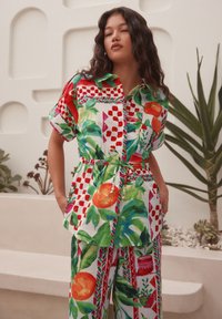 Pamut ruha élénk piros, narancs és zöld színű virág- és geometriai mintákkal. Laza szabás, övvel a deréknál és rövid ujjú.