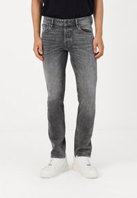 Grijze denim jeans met een slim fit, vervaagde textuur, vijf zakken ontwerp en een subtiele was effect, gecombineerd met witte sneakers.