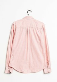 Light pink long-sleeve shirt with a button-down collar, featuring a back pleat and curved hem. Made of a woven cotton blend.
