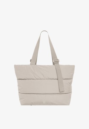 Beige gewatteerde draagtas met twee handvatten en een verstelbare schouderriem, met een klein "Got Bag"-logo vlakbij het midden onderaan.