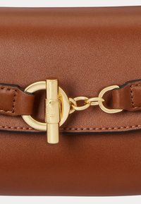 Barna bőr kézitáska arany színű lánc részlettel és csattal záródik. Simább textúrájú, látható varrásokkal díszítve.