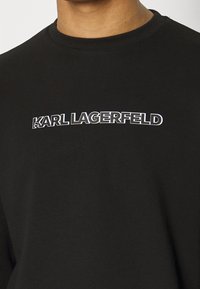 Felpa nera con logo bianco "KARL LAGERFELD"stampato sul petto. Realizzata in cotone, presenta un collo rotondo e una texture liscia.