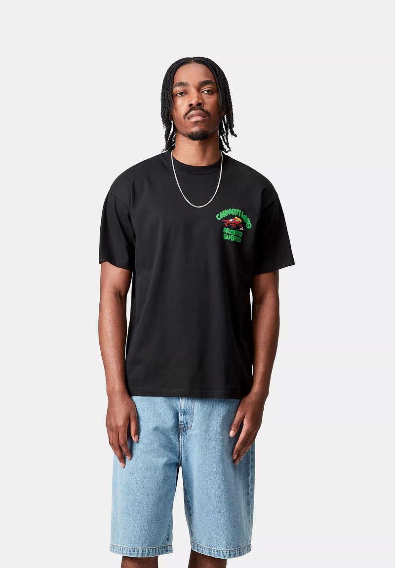 Black cotton t-shirt with green graphic design featuring text and a motif on the left chest. Paired with light blue denim shorts.