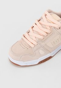 Roze suede tenisice s bijelim gumastim đonom i akcentima od gume. Imaju zaobljen vrh, perforirane detalje i ravne vezice. DC logo sa strane.