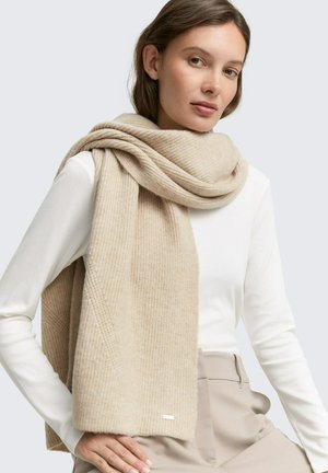 Sciarpa beige a costine realizzata in morbido materiale, drappeggiata in modo loose intorno al collo, caratterizzata da una texture sottile e un piccolo logo di accento.