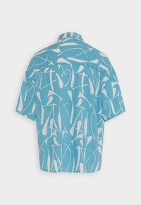 Camicia a maniche corte in tessuto blu con un motivo astratto bianco. Presenta un colletto a punta e una forma rilassata e squadrata.