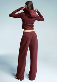 Bordeaux geknipte hoodie met een aangesloten stijl, gecombineerd met losse, hoog-wajande bordeauxbroeken. Gladde stof met subtiele rek en een elastische tailleband.