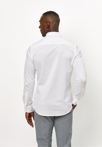 Witte langwerpige overhemd met een button-down kraag en een gladde, katoenen stof. Heeft een gebogen zoom en knoopmanchetten.