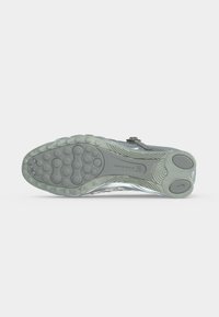 Η σόλα ενός παπουτσιού Nike Shox που δείχνει κυκλικά μοτίβα πρόσφυσης και μαξιλαράκια απορρόφησης κραδασμών σε γκρι και διαφανές καουτσούκ.
