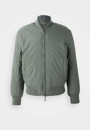 Olijfgroen bomberjack met een rits aan de voorkant, ribgebreide kraag en manchetten, met een gestructureerd patroon van herhaalde logo's en twee zijzakken.