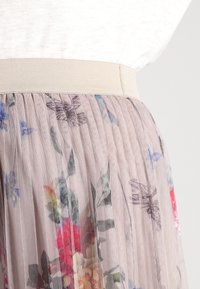 Falda plisada floral con una tela sheer de color rosa claro, un cinturón ancho elástico de color beige, que presenta patrones vibrantes de flores por toda la prenda.