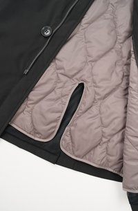 Schwarz Außensakko mit einer gesteppte hellbraunen Innenauskleidung und Netzelementen. Verfügt über einen Reißverschluss und einen Knopfverschluss.