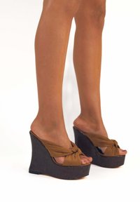 Sandali con zeppa marroni con dettaglio a nodo sulla parte superiore. Tacco in legno nero testurizzato che offre stabilità ed elevazione. Design aperto sul retro.