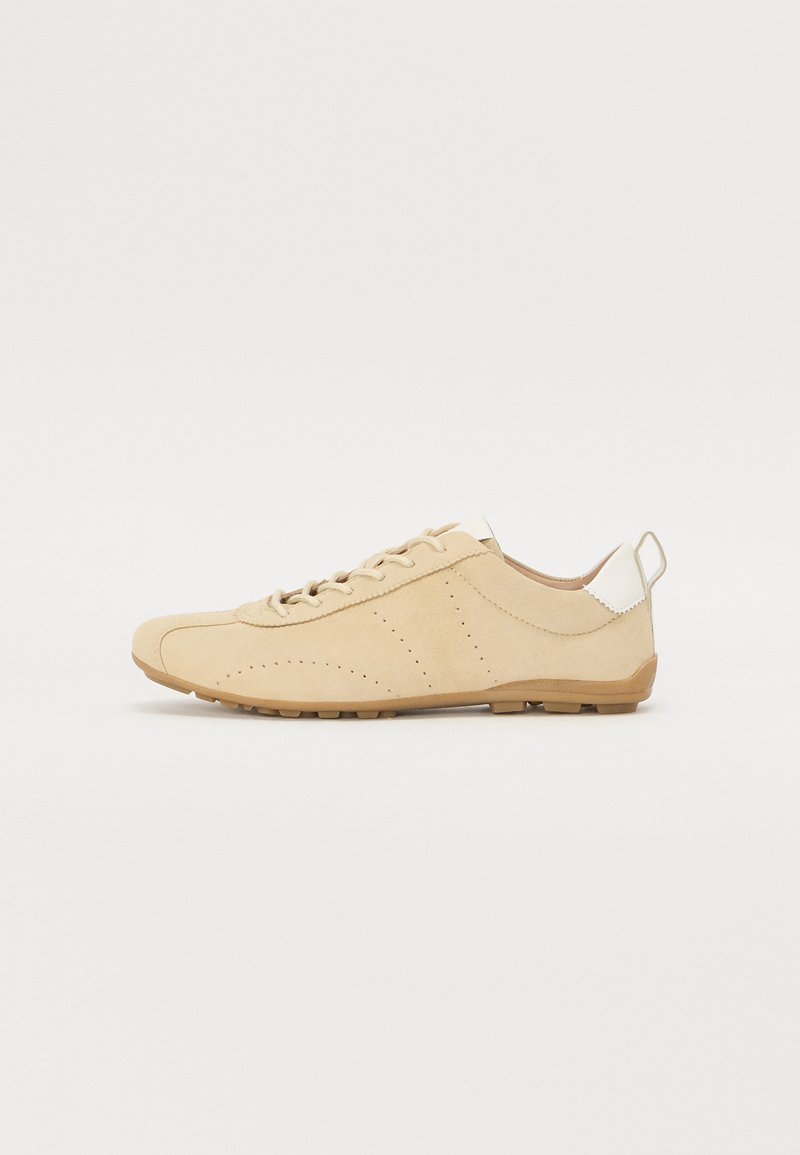 Beige semsket sko med rund tå, perforerte detaljer og en kontrastfylt hvit hæltab. Snøring design med gummisåle.