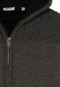 Szara bluza z kapturem na zamek błyskawiczny o prążkowanej fakturze, z czarnym kapturem wyściełanym polarem. Zapięcie na zamek błyskawiczny oraz metka wewnątrz przy szyi.